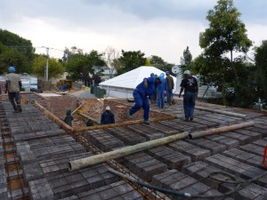 Standing on the first floor. You can see the piping waiting to be assembled and the reinforcing over which the concrete will be poured.